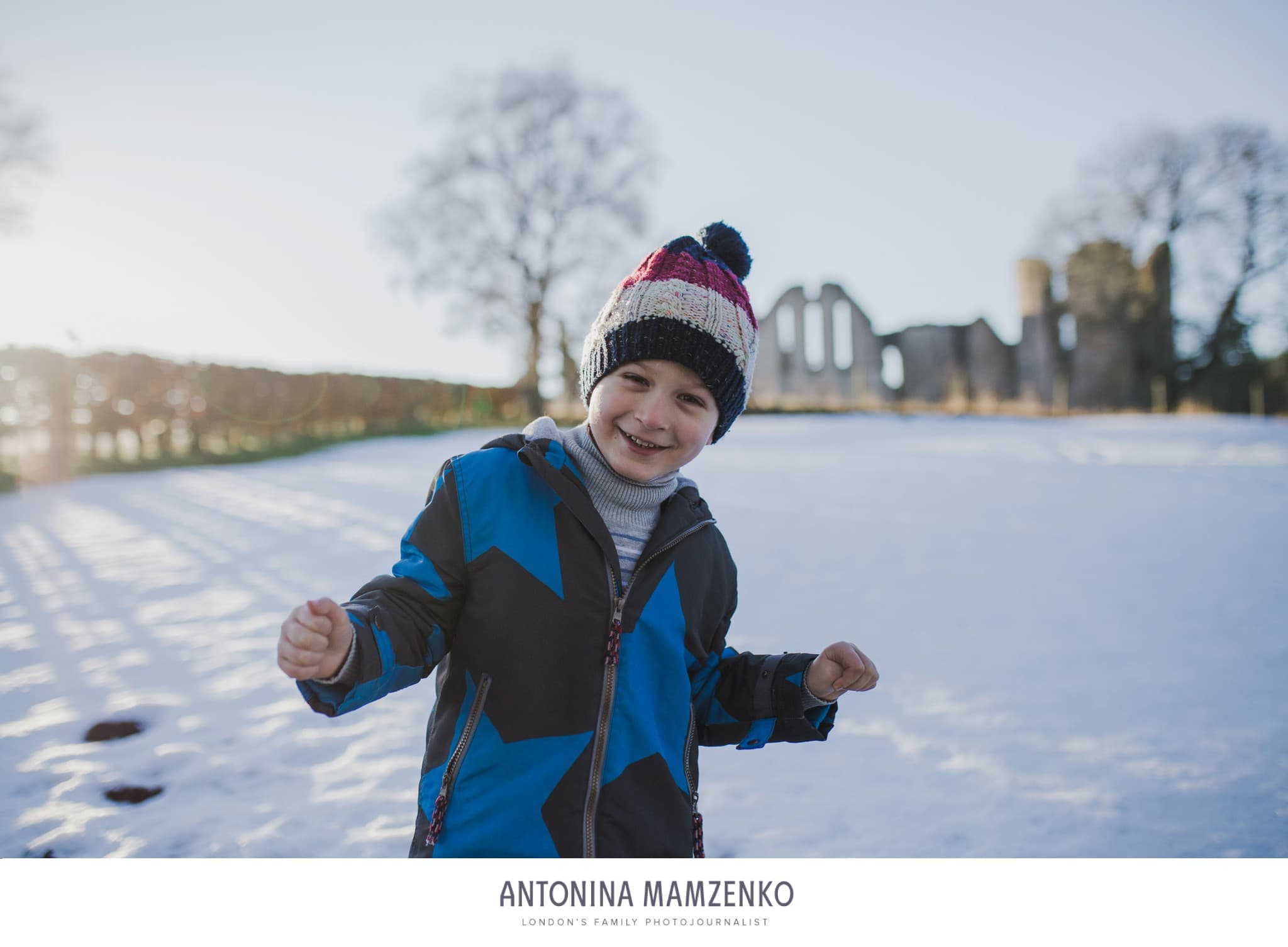 young boy playing in the snow with ruins of Kildrummy Castle in the background