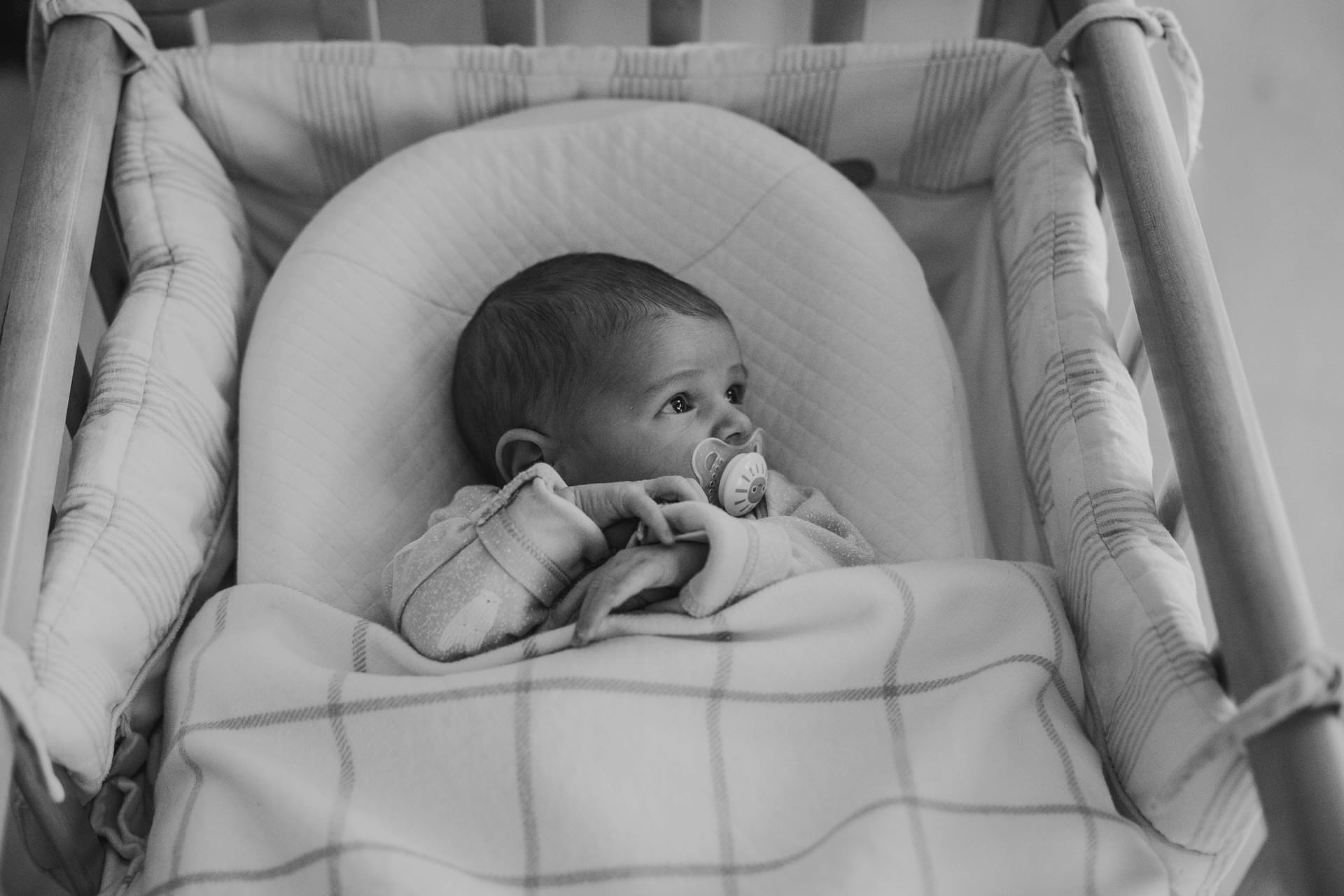 newborn baby in her cot with pacifier